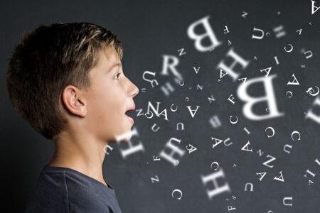 Junge beim Sprechen mit fliegenden Buchstaben – Sprachtherapie und fruehe Foerderung durch Logopaedie Holzwickede